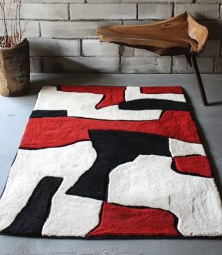 Abstract red, black, and white area rug with a geometric design placed in a modern room.