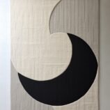Minimalist crescent abstract rug with bold black crescent on a textured ivory backdrop for modern interiors.