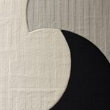 Minimalist crescent abstract rug with bold black crescent on a textured ivory backdrop for modern interiors.