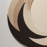 Circular crescent moon rug with a minimalist design in beige and black tones, perfect for modern decor.