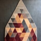 Triangular geometric rug in beige, maroon, and gray tones with a modern handcrafted design.