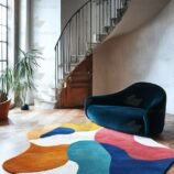 Bold multicolor rug in abstract shape under staircase and blue couch