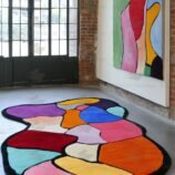 Abstract multicolor patchwork rug with black border placed in modern gallery-style room