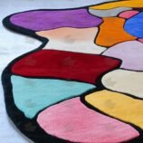 Abstract multicolor patchwork rug with black border placed in modern gallery-style room