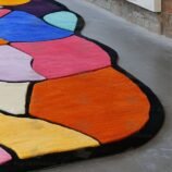 Abstract multicolor patchwork rug with black border placed in modern gallery-style room