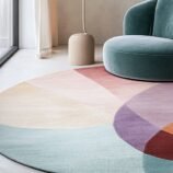 Round wool rug with abstract geometric color blocks in teal, orange, purple and cream – by Rugs Of Hindustan