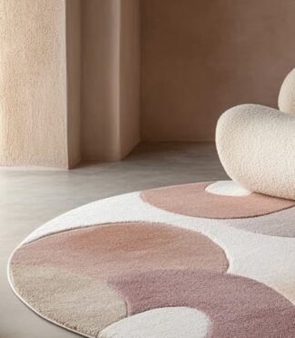 Abstract round wool rug in warm earth tones with modern sculptural chair and neutral interior