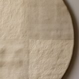 Minimalist hand-tufted round wool rug in beige with quadrant texture detailing by Rugs Of Hindustan