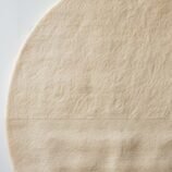 Minimalist hand-tufted round wool rug in beige with quadrant texture detailing by Rugs Of Hindustan