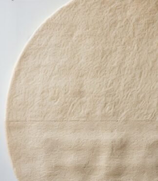 Minimalist hand-tufted round wool rug in beige with quadrant texture detailing by Rugs Of Hindustan
