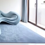 Minimalist hand-tufted solid blue wool rug under sculptural blue sofa in contemporary interior