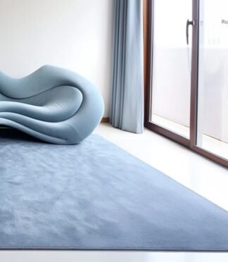 Minimalist hand-tufted solid blue wool rug under sculptural blue sofa in contemporary interior