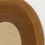 Concentric hand-tufted oval wool rug in gradient brown tones on white background