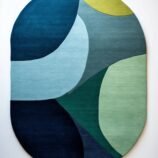abstract oval wool rug in ocean wave colors of green, teal, blue and yellow