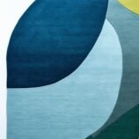 abstract oval wool rug in ocean wave colors of green, teal, blue and yellow