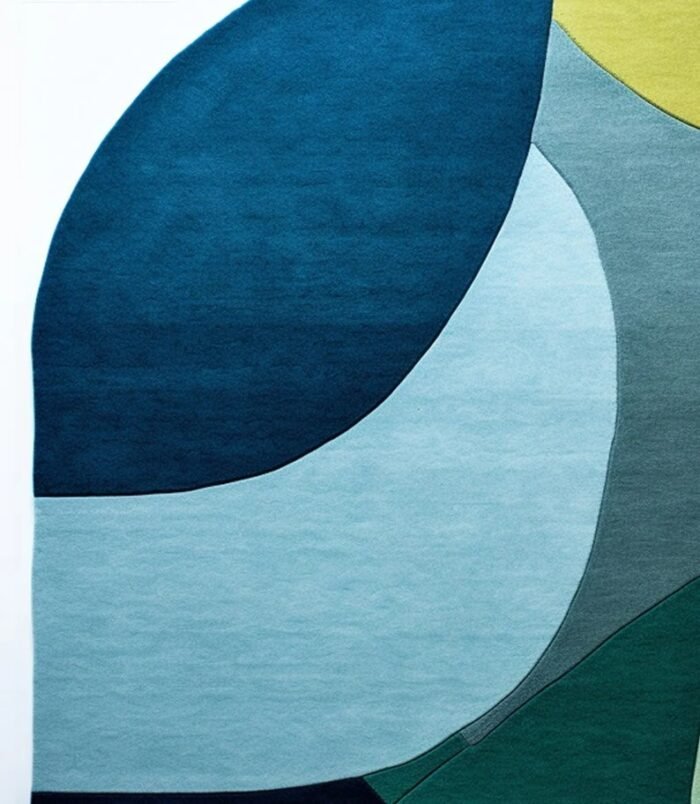 abstract oval wool rug in ocean wave colors of green, teal, blue and yellow