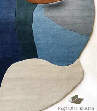 Modern abstract area rug in warm earth tones of orange, blue, and beige, handcrafted for modern interiors.