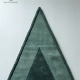 Handmade triangle wool rug in soft green with a minimalist geometric design, ideal for modern homes.