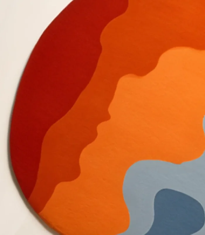 Bold abstract round area rug with vibrant orange, blue, and red hues, perfect for modern interiors.