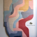 Handmade geometric abstract wool rug with layered design in warm and cool tones, perfect for modern home decor.