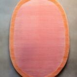 Peach pink oval rug with soft orange border on minimalist background – modern wool carpet