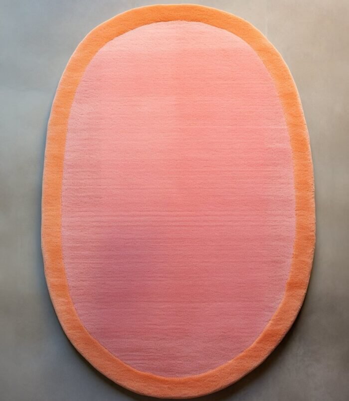 Peach pink oval rug with soft orange border on minimalist background – modern wool carpet