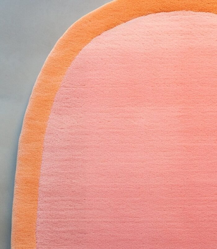 Peach pink oval rug with soft orange border on minimalist background – modern wool carpet